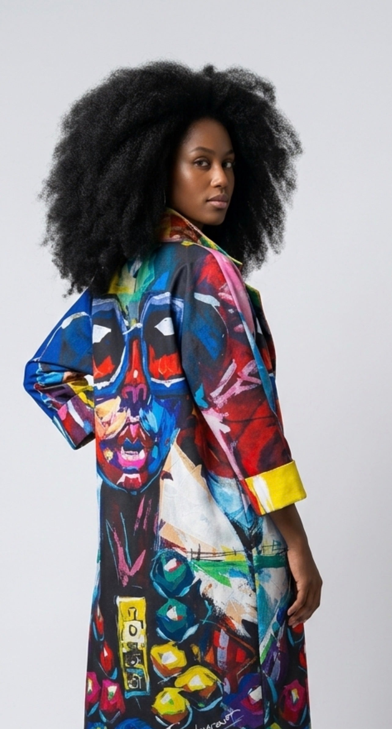 Woman wearing a colorful, art-inspired kimono style  coat against a plain background